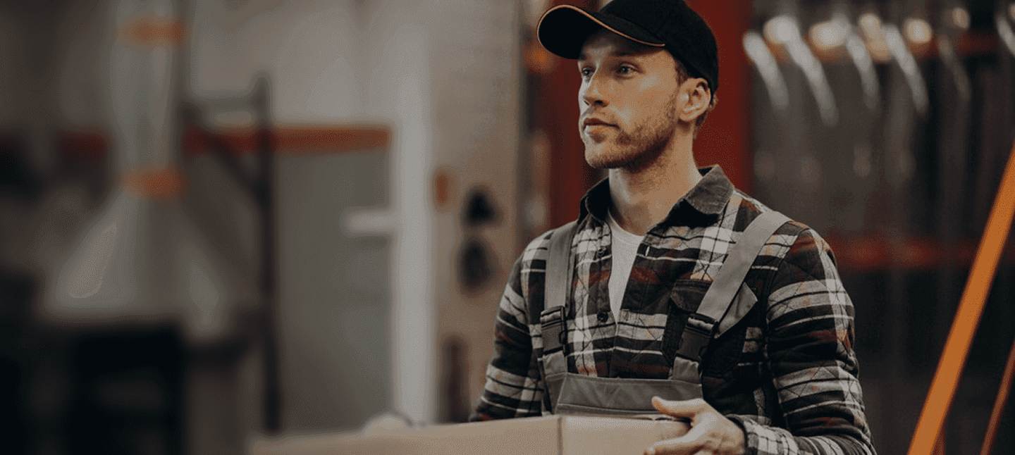 Homem com camisa xadrez e boné em ambiente industrial